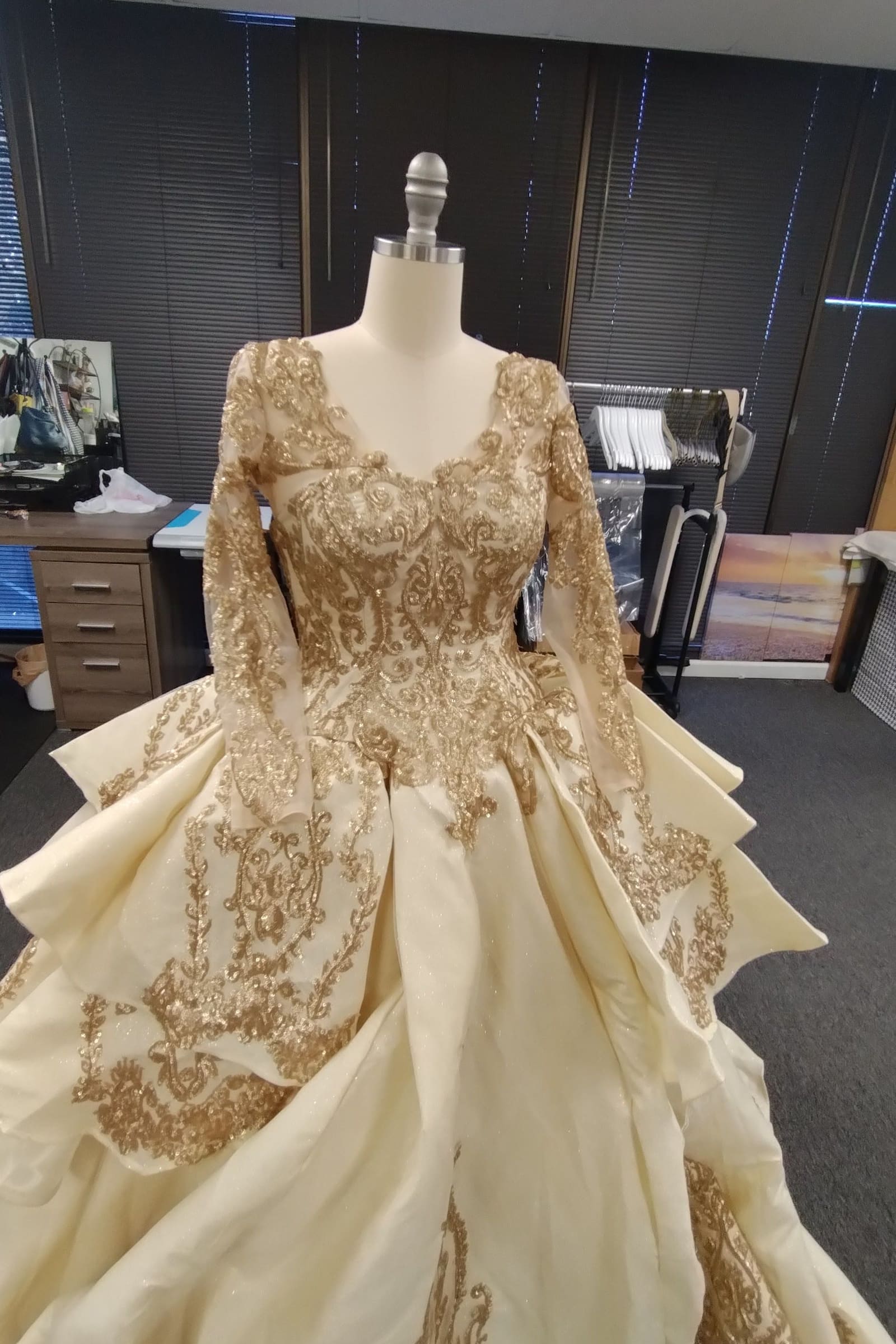 Champagne ball gown with long gold-embroidered sleeves and a tiered skirt