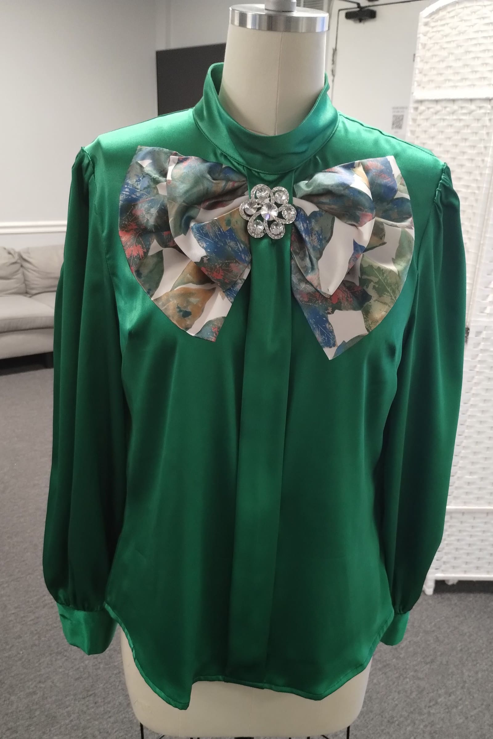 Emerald green silk blouse with an oversized printed bow and brooch