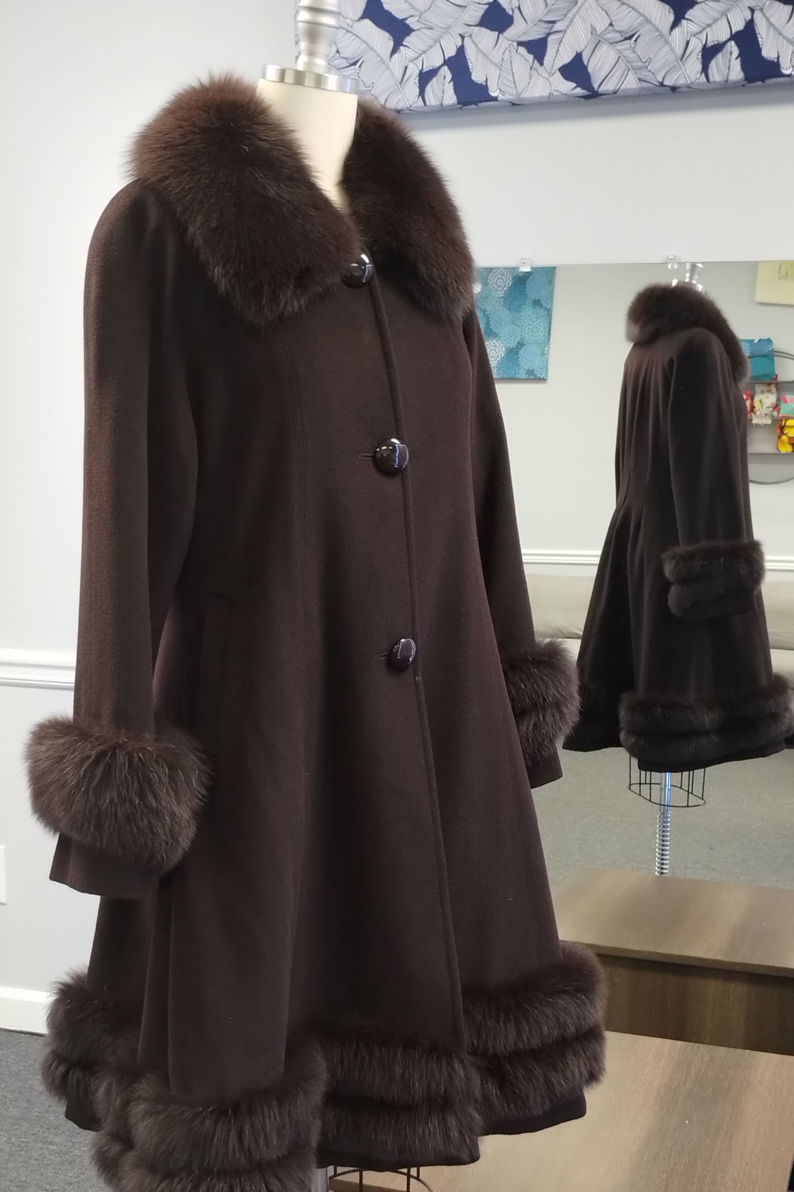 Brown wool coat with a fur collar, cuffs and hem on a dress form