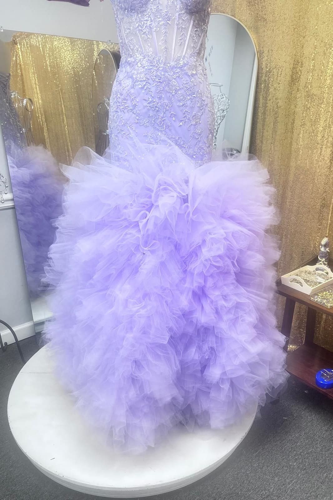 Lavender mermaid gown with a lace corset bodice and a skirt of tulle ruffles on the fitting platform