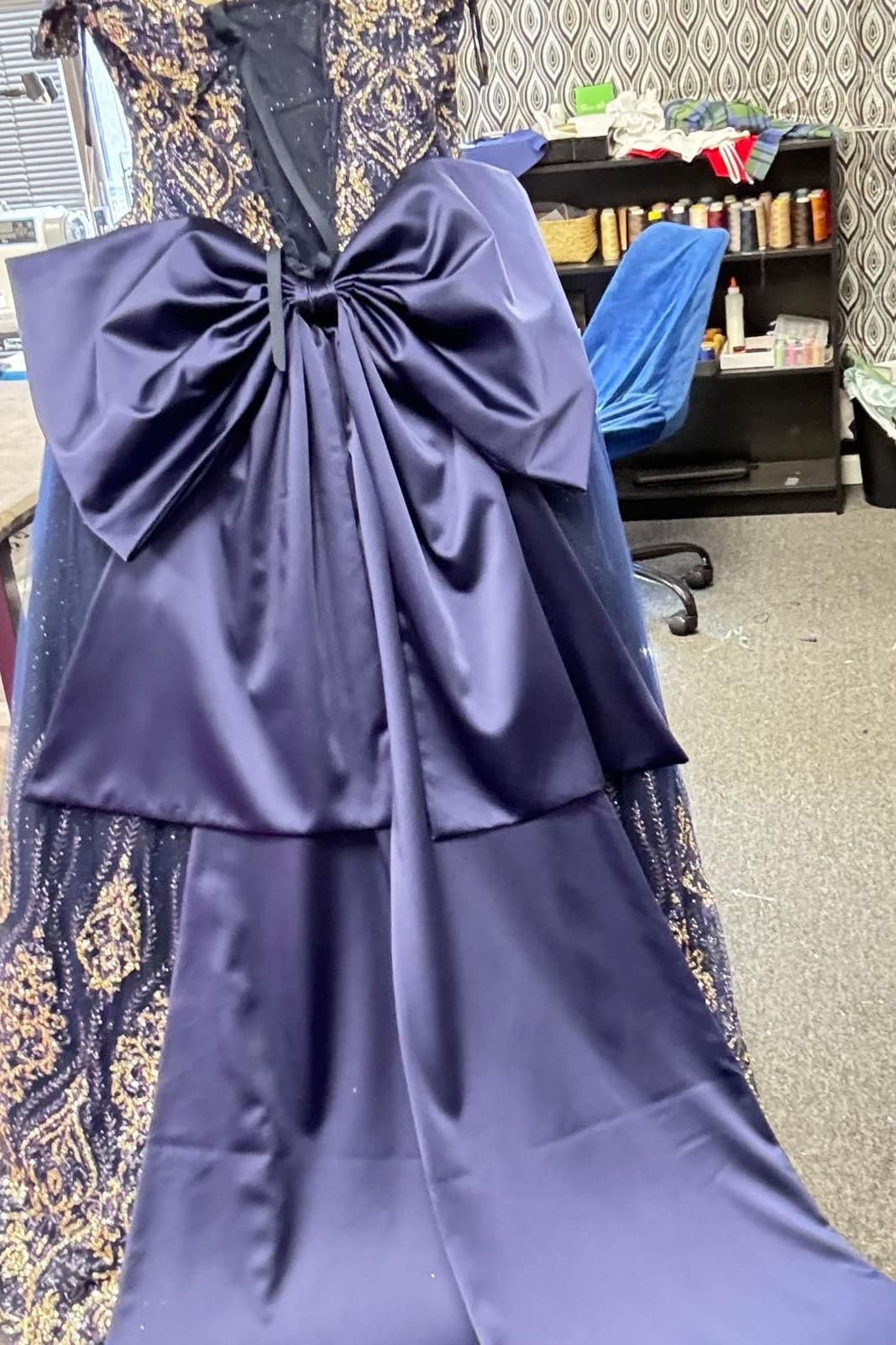 Navy satin wide-leg jumpsuit with an oversized bow at the back and a beaded lace overskirt on a dress form